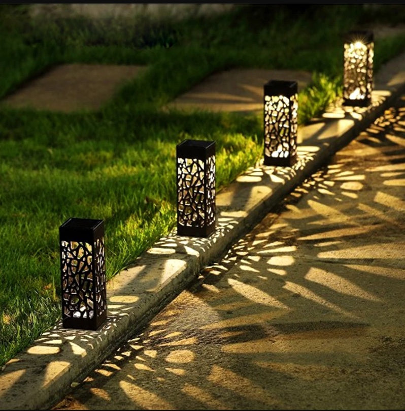 Decorative outdoor lanterns on a stone pathway with grass and sunlight.
