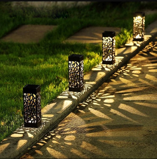 Decorative outdoor lanterns on a stone pathway with grass and sunlight.