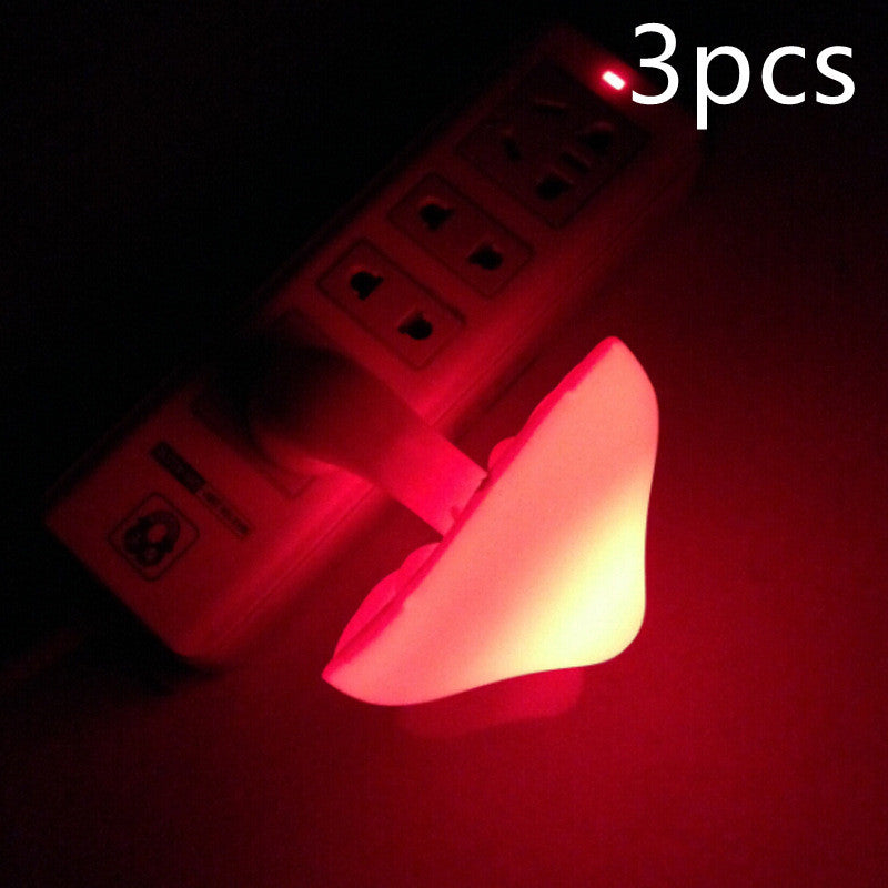 a mushroom shaped night light glowing red in front of a power outlet.