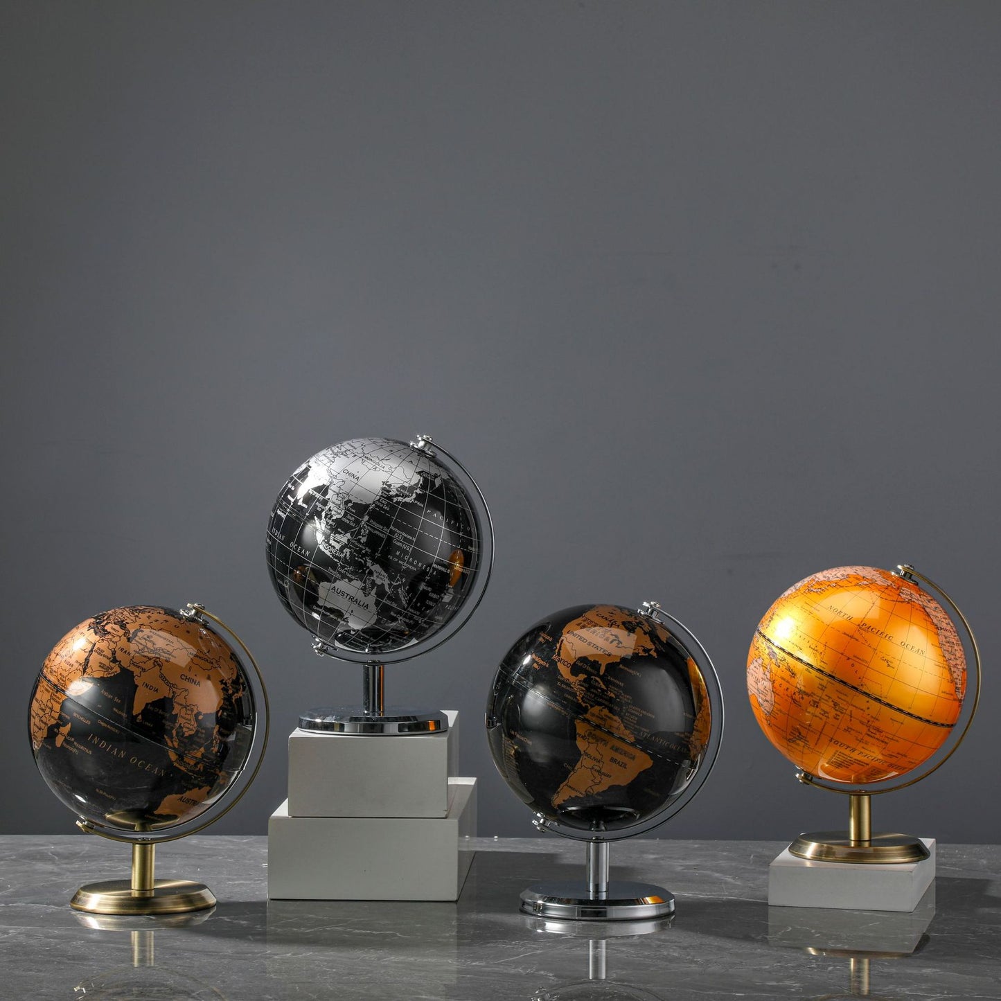 Set of four decorative globes on a gray surface with a dark gray background