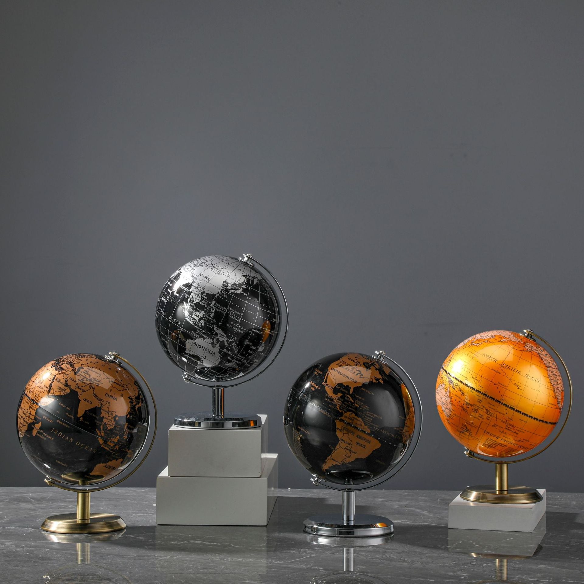 Set of four decorative globes on a gray surface with a dark gray background