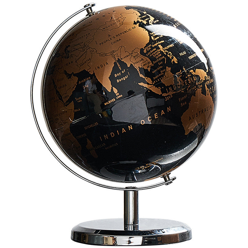 Black and gold world globe on a stand with a white background