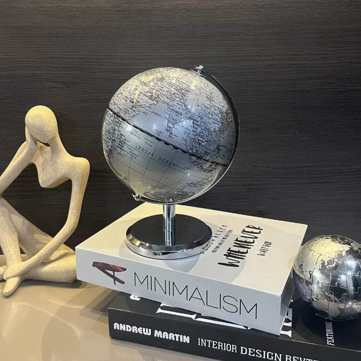 Globe on books with a decorative figure and another globe in the background