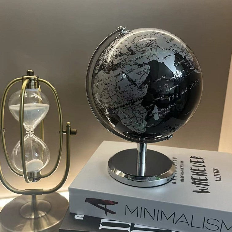 Black globe, hourglass, and book titled 'Minimalism' on a light background