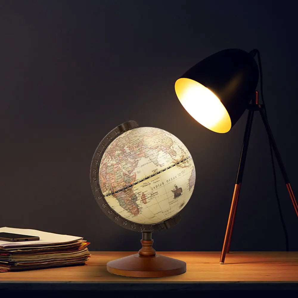 World globe on a wooden table with a lamp illuminating it against a dark background