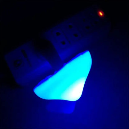 Blue mushroom-shaped ight bulb glowing in the dark with a power strip in the background.