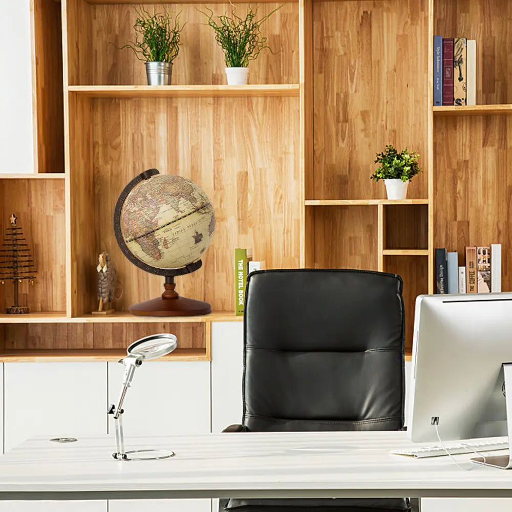 Modern office setup with a desk, chair, computer monitor, and decorative items including a vintage-style globe against a wooden bookshelf.